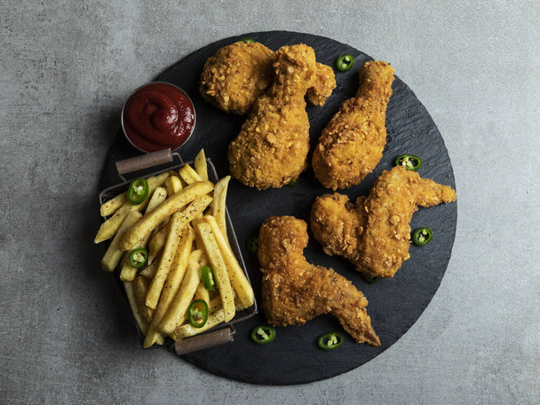 Breaded crispy fried chicken legs, wings, french fries and sauce - Foto, Imagen