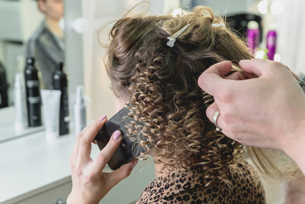 Nő a szépségszalonban csinál frizura és beszél mobiltelefonnal - Fotó, kép