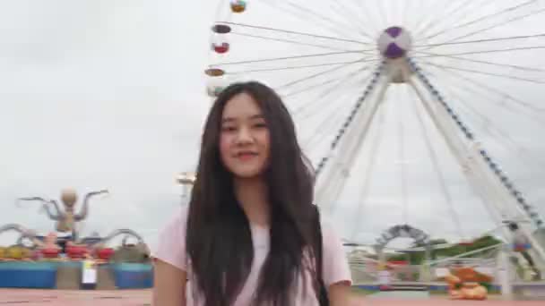 Krásná asijská žena kráčí do zábavního parku a hledá jízdu s ferring kola pozadí. Lidský životní styl a koncepce zábavy. Cestovní a rekreační koncept. Venku jezdí - Záběry, video