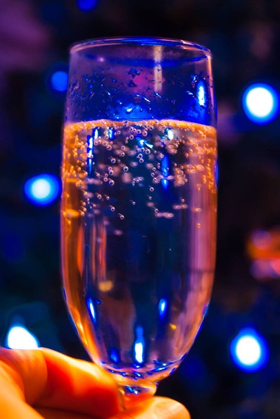Mavi bulanık ışıkların arka planına karşı bir kadeh şampanya. Sevgililer Günü 'nüz kutlu olsun. Noel Noel Noel' i. Mistik, köpüklü şarap. - Fotoğraf, Görsel