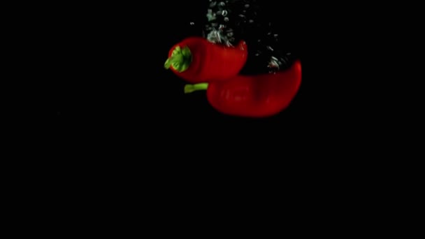 red pepper pouring into water, in dark background - Video, Çekim