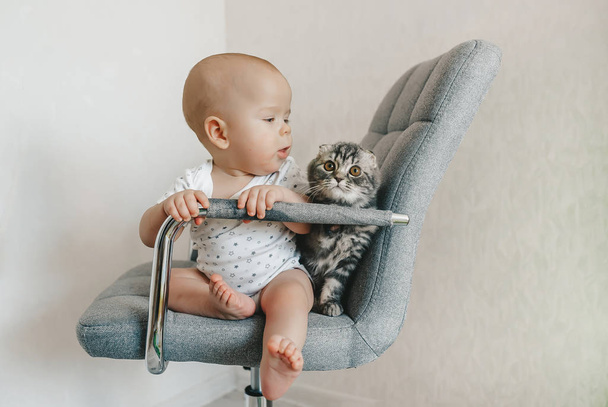 Dziecko z kotkiem na krześle w środku. - Zdjęcie, obraz