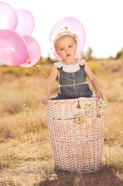 Baby girl playing in basket with balloons - Foto, afbeelding