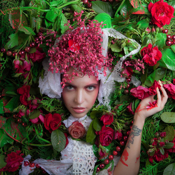 Female portrait in fairy tale stylization surrounded with natural flowers. - Foto, Imagen