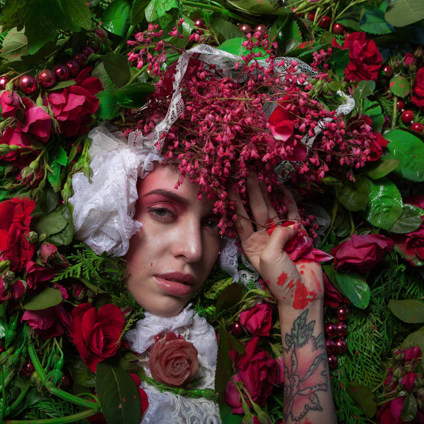 Female portrait in fairy tale stylization surrounded with natural flowers. - Фото, изображение