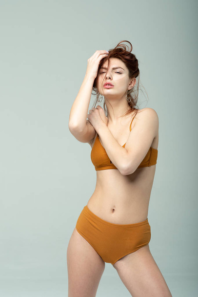 young beautiful girl posing in brown underwear in studio - Foto, imagen
