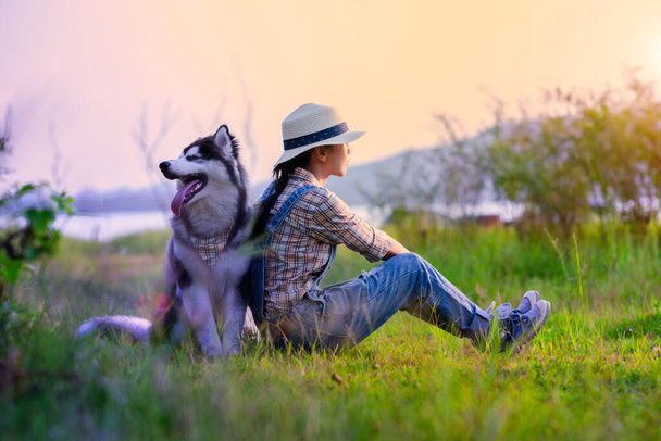 woman girl enjoy sitting with a puppy dog at foredst of lake river with sunset sweet time, friendship and relationship together in comfortable time - Fotó, kép