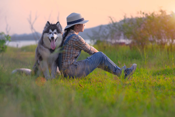 woman girl enjoy sitting with a puppy dog at foredst of lake river with sunset sweet time, friendship and relationship together in comfortable time - Foto, afbeelding
