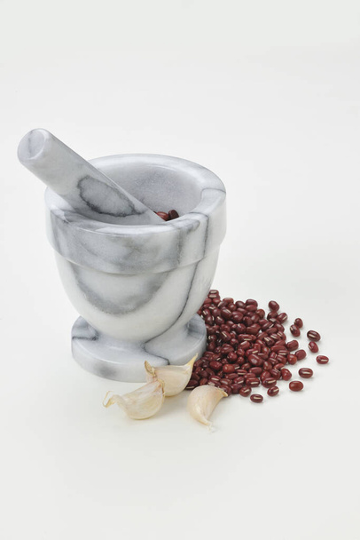 Portrét zátiší mramorové malty a paličky červené fazole a česneku na bílém pozadí - Fotografie, Obrázek