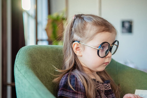 little toddler girl in glasses reading a book. back to school concept - Fotografie, Obrázek