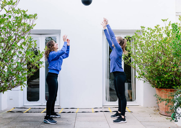 Duas mulheres jovens fazendo exercício em conjunto com a bola de medicina
 - Foto, Imagem
