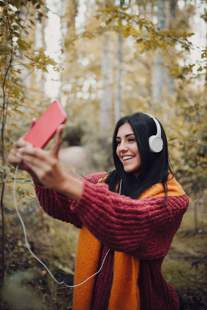 Nainen ottaa selfien puhelimellaan kuulokkeilla - Valokuva, kuva