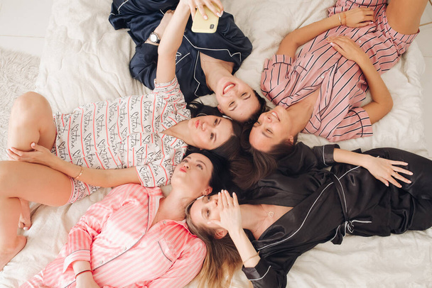 Красивые девушки в пижаме делают селфи на кровати
. - Фото, изображение