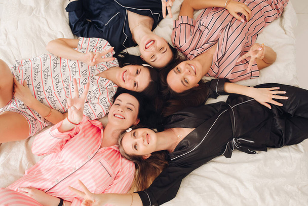Top view pihentető fiatal lány barátok feküdt az ágyon szórakozás pózol együtt - Fotó, kép