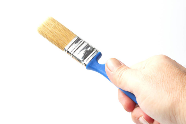 Paint brush with a blue handle in the right hand of a worker, close-up, white background. - Foto, immagini
