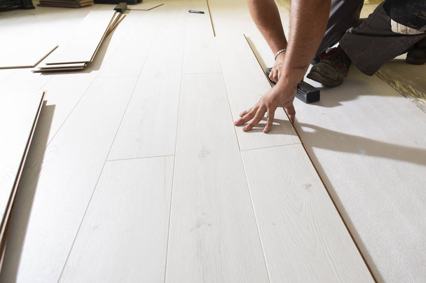 Man installing laminate floor in new house - Fotó, kép