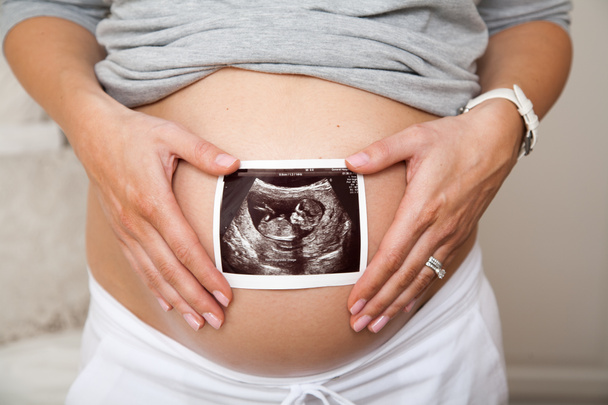 Крупный план беременной женщины, держащей ультразвук на животе - Фото, изображение