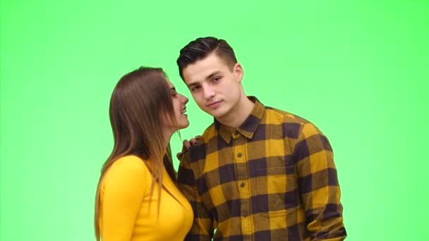 Woman is whispering a secret to her surprised young man on green background. Close up. Copy space. 4K. - Filmagem, Vídeo