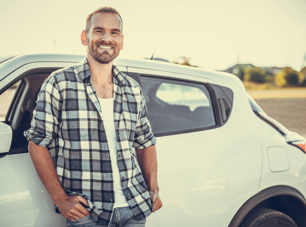 An attractive young man stands near a car. - Φωτογραφία, εικόνα