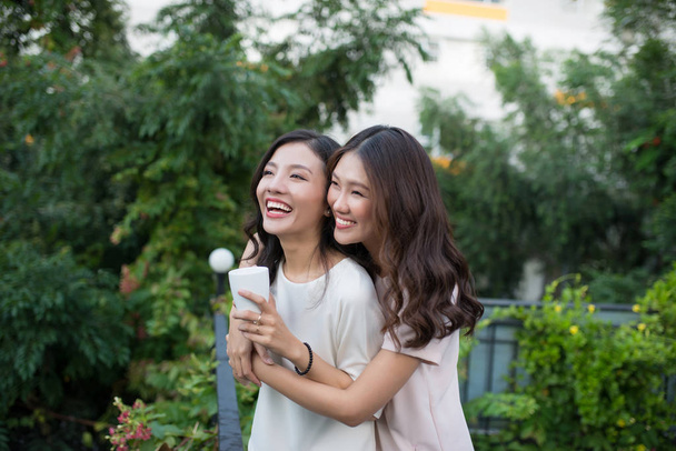 Két fiatal ázsiai nő ölelkezik az erkélyen. - Fotó, kép