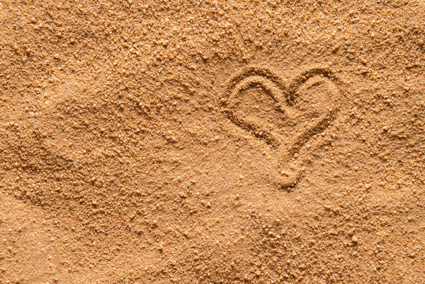 Μια καρδιά σχεδιάζεται στην επιφάνεια της άμμου. - Φωτογραφία, εικόνα
