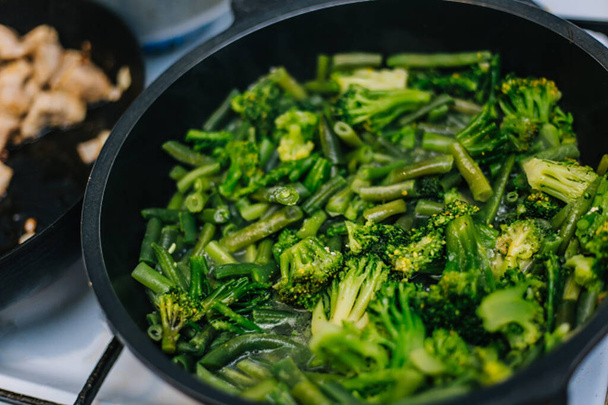 Cocinar verduras guisadas, brócoli y frijoles jóvenes en una sartén
. - Foto, Imagen