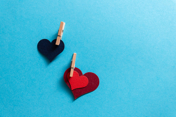 Herzen mit winzigen Wäscheklammern auf blauem Hintergrund. - Foto, Bild