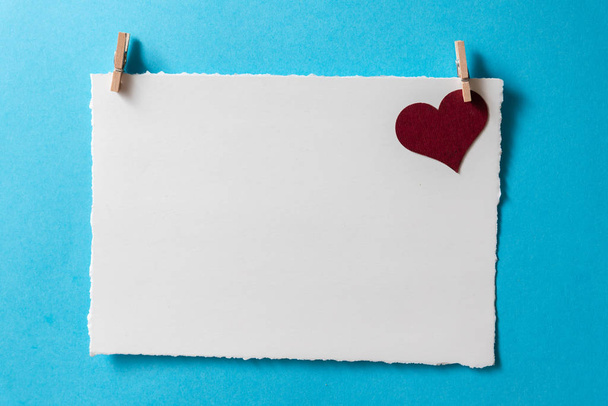 Modelo de cartão postal com coração de Borgonha e pequenas rotações de roupas em um fundo azul
. - Foto, Imagem