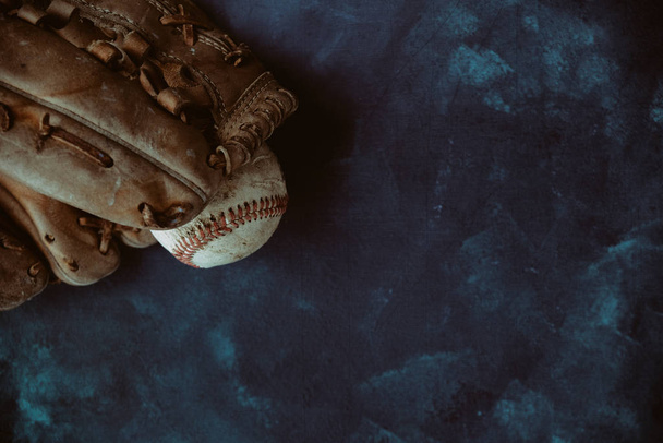Бейсбольна концепція розкриває м'яч у рукавичці на фоні текстури, стилі гранж. Вид зверху на спортивне обладнання з копіювальним простором
. - Фото, зображення