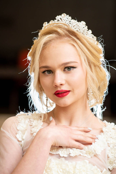 beautiful blonde girl in wedding dress with blue eyes and red lipstick on her lips - Фото, зображення