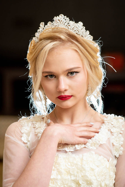 beautiful blonde girl in wedding dress with blue eyes and red lipstick on her lips - Foto, afbeelding