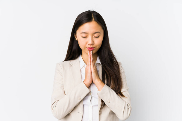 Νεαρή Κινέζα επιχειρηματίας απομονωμένη κρατώντας τα χέρια στην προσευχή κοντά στο στόμα, αισθάνεται αυτοπεποίθηση. - Φωτογραφία, εικόνα