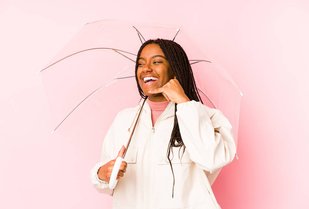 若いアフリカ系アメリカ人の女性は、指で携帯電話の呼び出しジェスチャーを示す孤立傘を保持. - 写真・画像