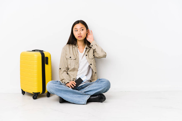 junge chinesische Reisende Frau sitzt mit einer Bordkarte versucht, einen Klatsch zu hören. - Foto, Bild