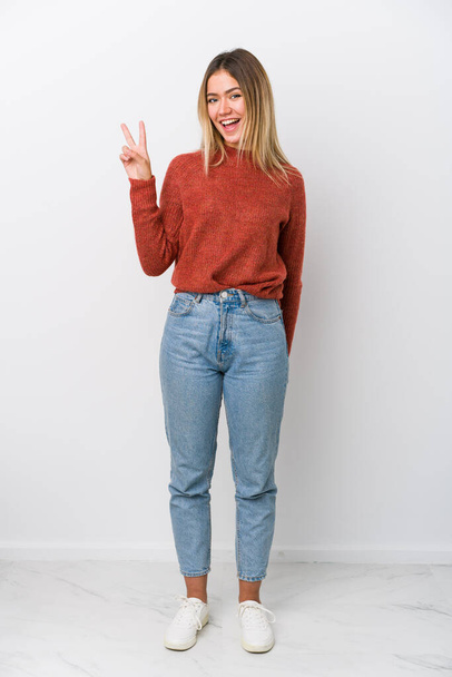 Full body young caucasian woman joyful and carefree showing a peace symbol with fingers. - Photo, Image