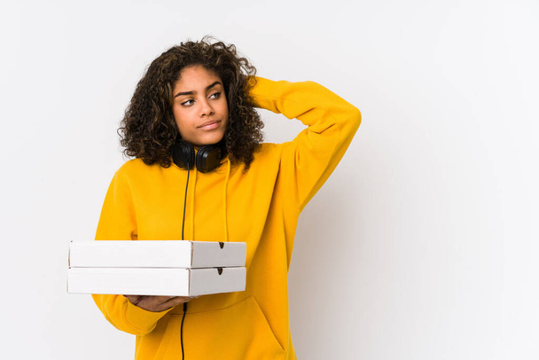 若いアフリカ系アメリカ人の学生の女性はピザを頭の後ろに触れ、考え、選択をする. - 写真・画像