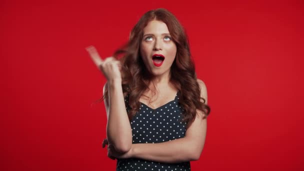 Portrait of young thinking pondering woman having idea moment pointing finger up on red studio background. Smiling happy girl showing eureka gesture. - Metraje, vídeo