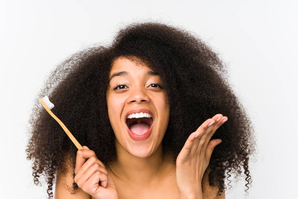 Giovane donna afro in possesso di una spazzola isolata che celebra una vittoria o un successo
 - Foto, immagini