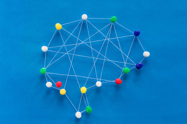 neurális hálózati koncepció, többszínű csapok és fehér szálak alkotnak egy képet az agy kék alapon - Fotó, kép