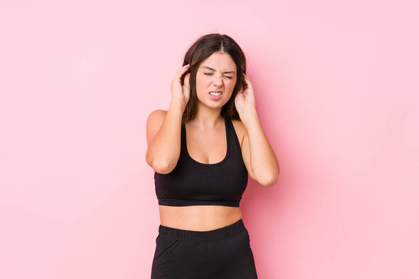 Young fitness caucasian woman isolated covering ears with hands. - Фото, зображення