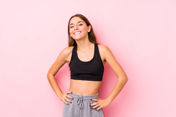 Young caucasian fitness woman posing in a pink background confident keeping hands on hips. - Photo, Image