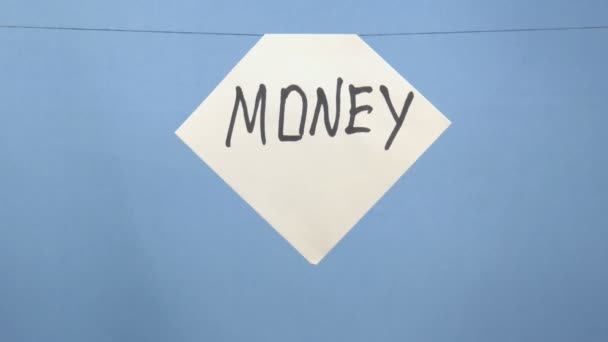 Verbranden en roken van wit vel papier met een zwarte inscriptie "geld" op een blauwe achtergrond - Video