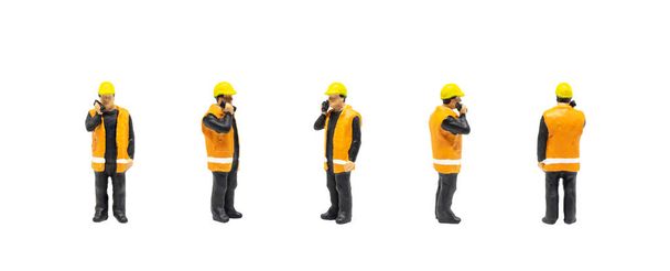 Miniature figurine character as worker wearing safety vest and posing in posture isolated on white background. - Photo, Image