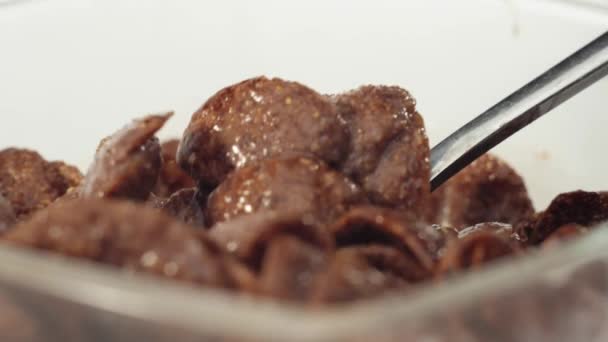 Fresh healthy food. Spoon grabs chocolate cereal flakes with milk from transparent bowl on a white background. The concept of healthy breakfast, clean eating, dieting, vegetarian, vegan food. Close up - Footage, Video
