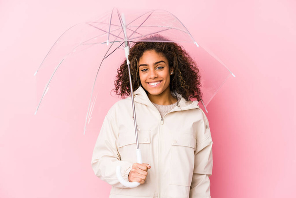 Mladá africká Američanka drží deštník šťastný, usmívající se a veselý. - Fotografie, Obrázek