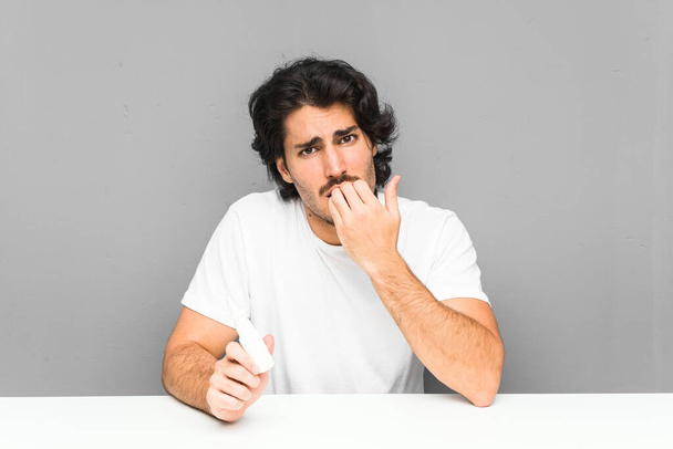 Mladý muž drží sprej kousání nehty v nose, nervózní a velmi úzkostlivý. - Fotografie, Obrázek