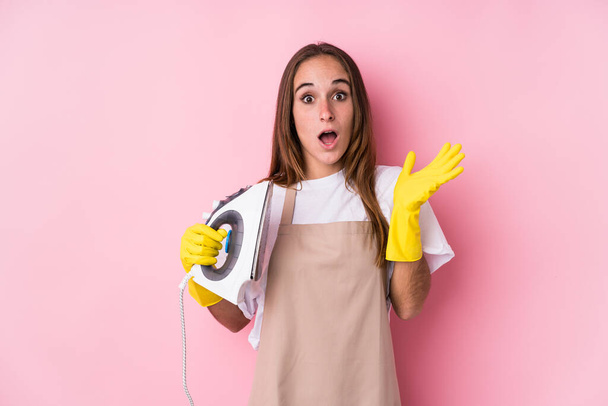 Young caucasian woman with clothes iron isolated surprised and shocked. - Photo, image
