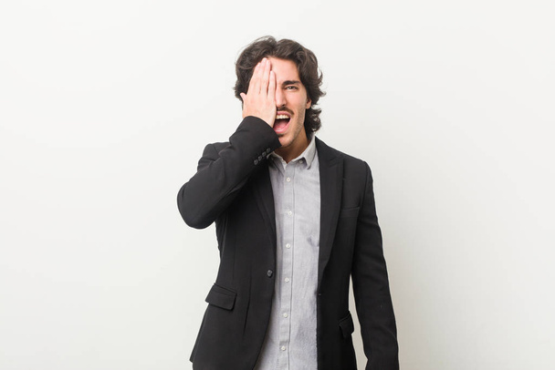 Young business man against a white background having fun covering half of face with palm. - 写真・画像