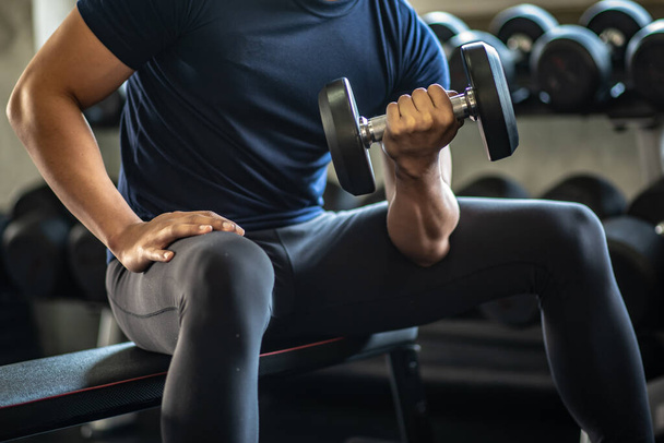 Nahaufnahme sportlicher Mann beim Heben der Gewichte mit Bizeps im Fitnessstudio. - Foto, Bild