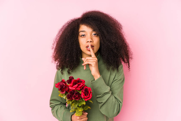 Nuori afro nainen tilalla ruusuja eristetty Nuori afro nainen tilalla ruusunvartija salaisuus tai pyytää hiljaisuutta
. - Valokuva, kuva